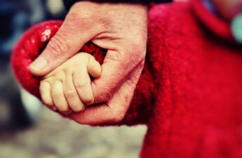 Mano de anciano coge la de un niño