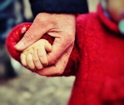 Mano de anciano coge la de un niño